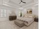 Primary bedroom with ceiling fan, tray ceilings, large bed, bench and shuttered windows at 162 Arabella Ct, Cary, NC 27518