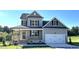 Charming two-story home features a covered porch, manicured lawn, and a two car garage at 169 Tigris Ct, Zebulon, NC 27597