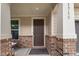 Charming front porch featuring brick accents, a brown door, and a welcoming entryway at 1715 Capstone Dr, Durham, NC 27713