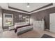 Inviting bedroom with soft carpet, tray ceiling, and windows offering a view of the neighborhood at 1715 Capstone Dr, Durham, NC 27713