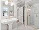 Elegant bathroom featuring a pedestal sink, tiled floors, and a glass-enclosed shower with gold accents at 202 High St, Carrboro, NC 27510