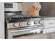 Close-up of a stainless steel gas range stove top with silver knobs and granite countertops at 202 High St, Carrboro, NC 27510