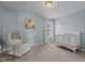 Well-lit bedroom featuring a crib, chair, and picture window at 2220 Rainy Lake St, Wake Forest, NC 27587