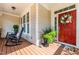 Cozy front porch with rocking chairs and a festive wreath on the red front door at 2739 Elderberry Ln, Apex, NC 27539
