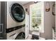 Modern laundry room with stackable washer and dryer unit, bright window, and storage at 2739 Elderberry Ln, Apex, NC 27539
