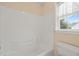 Bright bathroom featuring a tub with white wall surround and a window adorned with lace curtains at 2782 N Shiloh Rd, Garner, NC 27529
