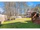 Green backyard features a wooden fence and mature trees, offering privacy and space at 4 Teahouse Ct, Durham, NC 27707