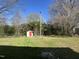 A serene backyard featuring a storage shed surrounded by lush trees and greenery at 512 Texas Ave, Burlington, NC 27217