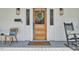 Elegant wooden front door with sidelights and a decorative wreath, complemented by rocking chairs at 523 N Main St, Graham, NC 27253