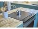 Bright kitchen island with hardwood top, cooktop, and custom blue cabinets at 523 N Main St, Graham, NC 27253