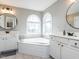 Elegant bathroom featuring dual sinks, a corner bathtub beneath arched windows, and ample counter space at 543 Chatham Forest Dr, Pittsboro, NC 27312