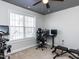Bedroom with large window, black ceiling fan, carpeted floor and home exercise equipment at 543 Chatham Forest Dr, Pittsboro, NC 27312