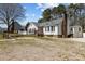 Exterior view of a white home with a brick chimney, front deck, and gravel yard at 5437 Grasshopper Rd, Raleigh, NC 27610