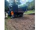 A dump truck deposits mulch onto a property that is undergoing some landscaping, with trees in the background at 5437 Grasshopper Rd, Raleigh, NC 27610