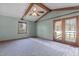 Living room with blue walls, wood beam ceiling, fan, and double doors leading outside at 5437 Grasshopper Rd, Raleigh, NC 27610