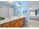 Bright blue bathroom with double sinks, wood cabinets and large mirror at 5569 Sea Daisy Dr, Raleigh, NC 27606