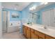 Bright blue bathroom with double sinks, wood cabinets and separate tub and shower at 5569 Sea Daisy Dr, Raleigh, NC 27606