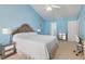 Light-filled bedroom features vaulted ceiling, blue walls, neutral carpet and two nightstands at 5569 Sea Daisy Dr, Raleigh, NC 27606