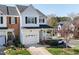 Exterior of a two-story townhome showcasing lush landscaping, a brick accent, and a one car garage at 5569 Sea Daisy Dr, Raleigh, NC 27606
