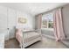 Charming bedroom features a white bed with pink bedding, elegant chandelier, and window with soft pink curtains at 6108 Norwood Place Ct, Raleigh, NC 27613