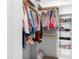 Organized walk-in closet with clothes hanging on a gold rod and shelving with baskets and shoes at 6108 Norwood Place Ct, Raleigh, NC 27613