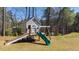 View of the custom-built playhouse in the backyard, complete with slide, swing, and climbing dome, offering a fun space at 6108 Norwood Place Ct, Raleigh, NC 27613