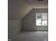 Unfinished attic space with angled ceiling and a large window providing natural light at 65 Stream View Way, Spring Hope, NC 27882