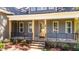 Stone stairs lead to a covered porch featuring a glass front door, windows, and black metal railing at 65 Stream View Way, Spring Hope, NC 27882