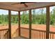 Covered patio with wood railings overlooking a clearing with forested area in the background at 65 Stream View Way, Spring Hope, NC 27882