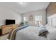 Comfortable bedroom features an accent brick wall, two bright windows, and a wooden dresser with mounted TV at 75 Red Crabapple Ct, Clayton, NC 27520
