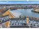 Aerial view of townhomes near a serene lake and walking trail, surrounded by lush greenery and mature trees at 818 Lilyquist Way, Wake Forest, NC 27587