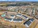 An aerial view captures a neighborhood with townhomes, complemented by mature trees and a lake with a pool and recreation area at 818 Lilyquist Way, Wake Forest, NC 27587