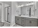 Bathroom featuring a double vanity with gray cabinets, quartz countertop, and a glass shower at 818 Lilyquist Way, Wake Forest, NC 27587