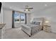 Bedroom with a tufted headboard, ceiling fan, two side tables, and a view of the water outside at 818 Lilyquist Way, Wake Forest, NC 27587