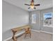 Neutral bedroom with a ceiling fan, two windows, and a rustic wooden desk with matching chair at 818 Lilyquist Way, Wake Forest, NC 27587