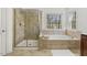 Bright bathroom featuring soaking tub, glass enclosed shower, and tiled floor at 8215 Cushing St, Raleigh, NC 27613