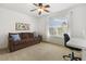 Bedroom featuring carpet, couch, ceiling fan, large window with backyard views, and writing desk at 8215 Cushing St, Raleigh, NC 27613
