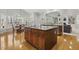 Open-concept kitchen with island, granite countertops, wood cabinets, hardwood floor and large windows looking to living room at 8215 Cushing St, Raleigh, NC 27613