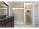 A stylish bathroom features a glass-enclosed shower, shelving with stacked towels, and a dark vanity at 8310 Wycombe Ln, Raleigh, NC 27615
