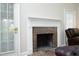 Close-up of the fireplace with brick surround, a white mantel, and bright natural lighting at 8310 Wycombe Ln, Raleigh, NC 27615