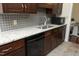 An upgraded kitchen with granite countertops, tile backsplash, dark wood cabinets, and stainless steel appliances at 8310 Wycombe Ln, Raleigh, NC 27615
