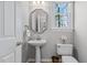 Stylish half bathroom featuring a pedestal sink, octagonal mirror, and natural light at 101 Barriedale Cir, Cary, NC 27519