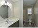Well-lit bathroom featuring a modern vanity with round mirror, and a tiled shower/tub combo at 10317 Lake Wheeler Rd, Fuquay Varina, NC 27526