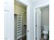 Walk-in closet next to a bathroom with white fixtures and open storage at 10317 Lake Wheeler Rd, Fuquay Varina, NC 27526