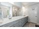 Well-lit bathroom with double vanity, large mirror, gray cabinets and combination tub and shower at 105 Village Dr, Broadway, NC 27505