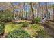 A lush backyard featuring green grass, mature trees, and a fire pit in the distance at 1052 Mills Street, Raleigh, NC 27608