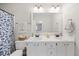 Well-lit bathroom featuring a double sink vanity, decorative shower curtain, and a view into an adjacent bedroom at 1052 Mills Street, Raleigh, NC 27608