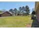 Expansive backyard featuring a lush lawn, tall trees, and black chain-link fence, creating a serene outdoor space at 1055 Tilghman Rd, Dunn, NC 28334