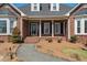 Charming front porch featuring a decorative glass door, white columns, black shutters and manicured shrubbery at 1055 Tilghman Rd, Dunn, NC 28334