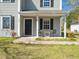 Close-up of the charming front porch with seating, a dark front door, and light gray siding at 106 Mingocrest Dr, Knightdale, NC 27545